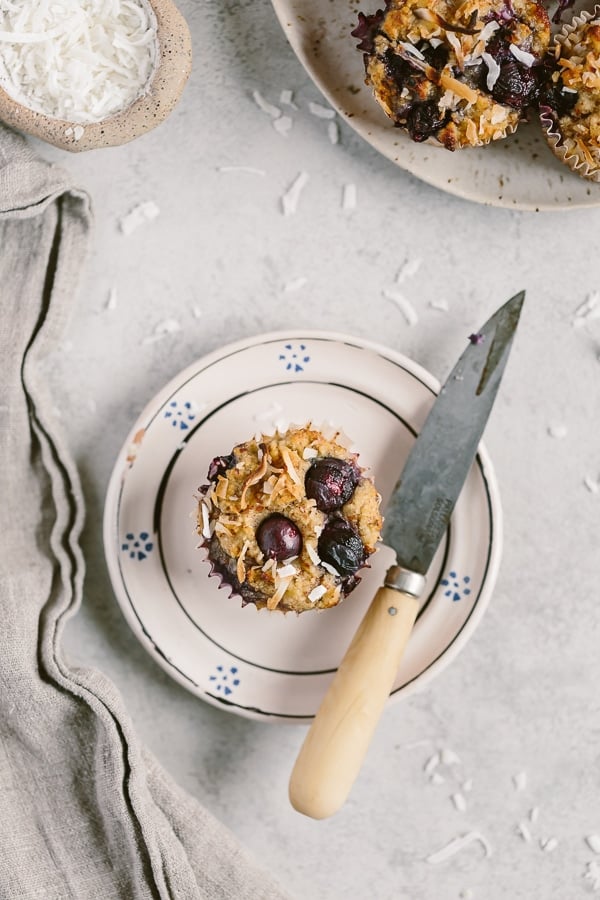 A muffin on a plate with a knife on the side