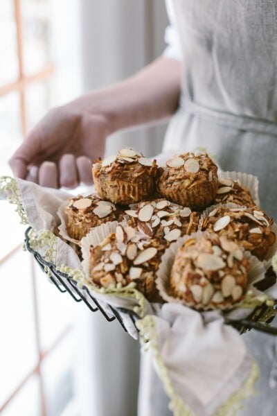 A woman is holding a basket of Parsnip Morning Glory Bran Muffins