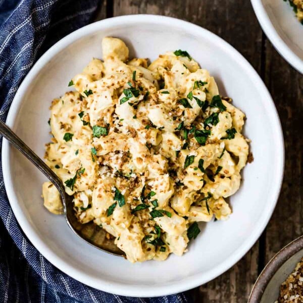 A bowl of homemade vegan mac and cheese recipe is garnished with parsley and breadcrumbs