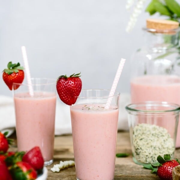 A few glasses of strawberry banana yogurt smoothie with straws
