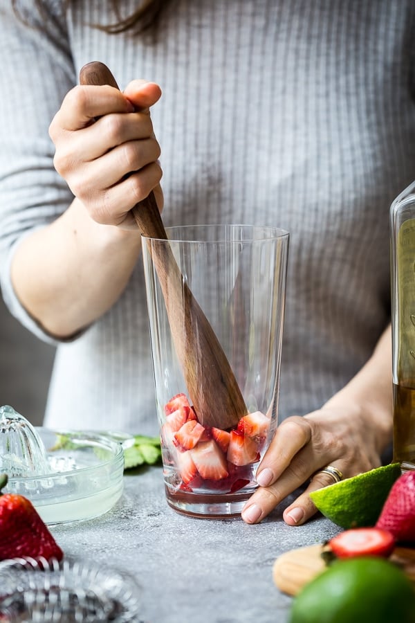 A woman is muddling strawberries
