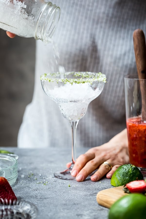 A woman is placing ice in a margarita glass