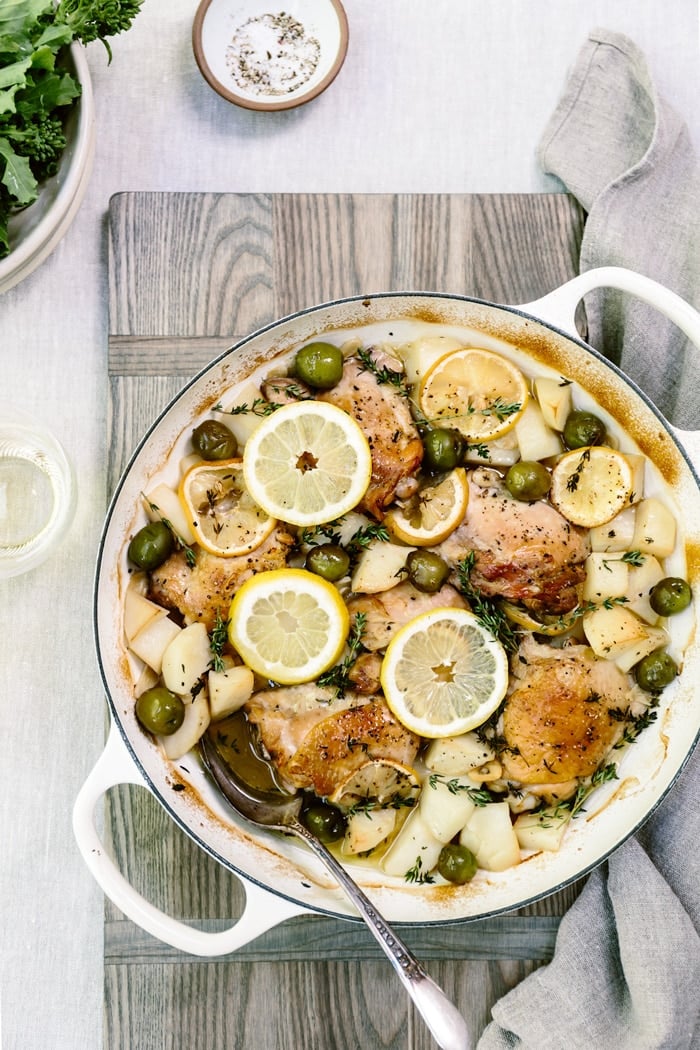 Recipe for Mediterranean Lemon Chicken with Olives and Potatoes in a large pot on a wooden cutting board
