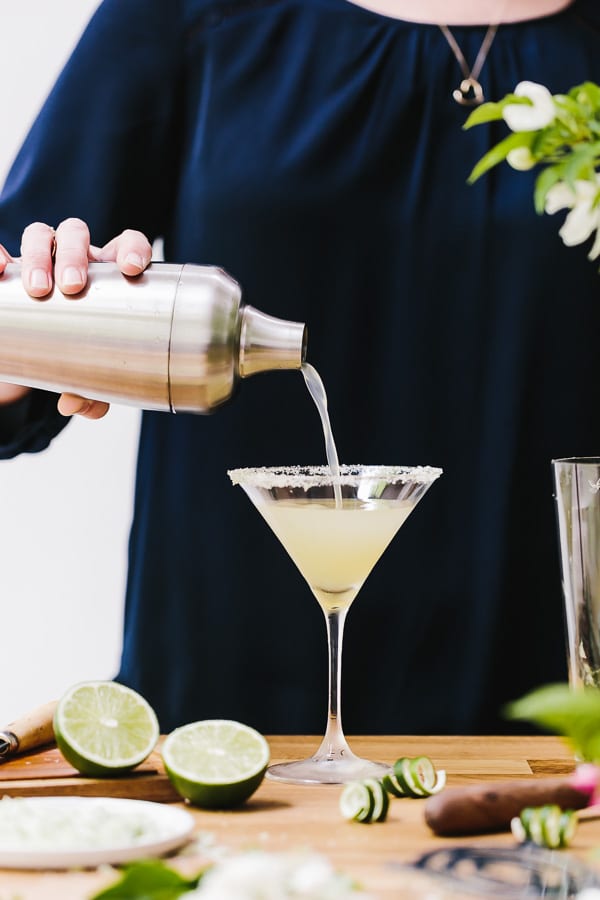 A woman is pouring a Recipe of Lime Martini made with mint flavored simple syrup into a glass