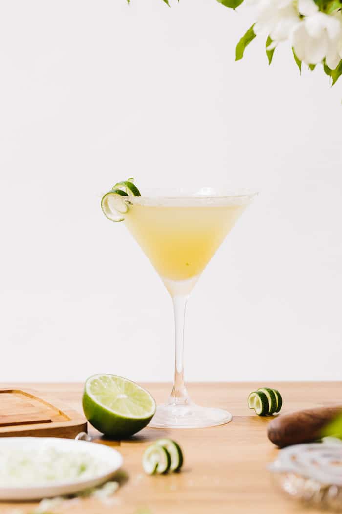 A glass of Lime Drop Martini made with mint flavored simple syrup garnished with lime skin