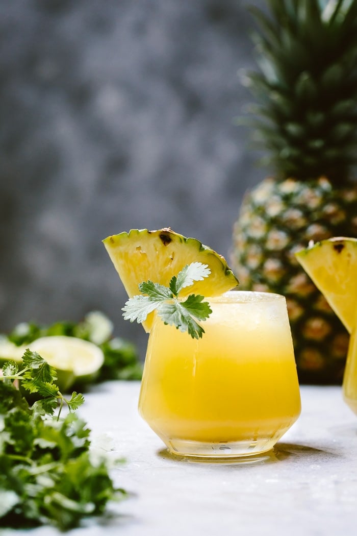 A glass of Spicy Pineapple Jalapeno Mezcalita garnished with pineapple and cilantro