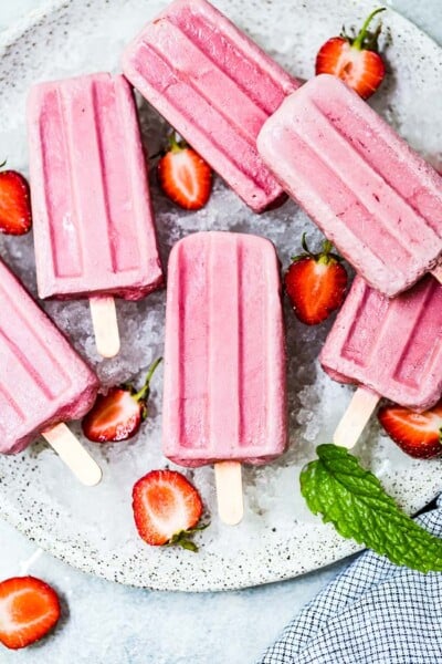 Coconut milk popsicles on a plate with strawberries