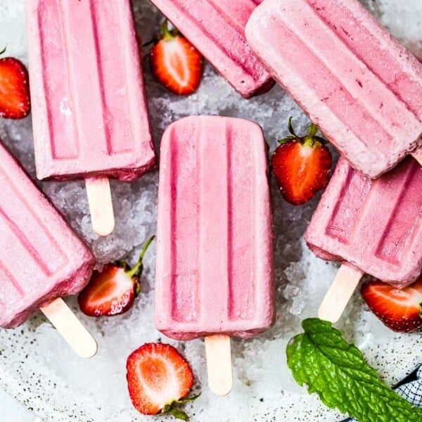 Coconut milk popsicles on a plate with strawberries