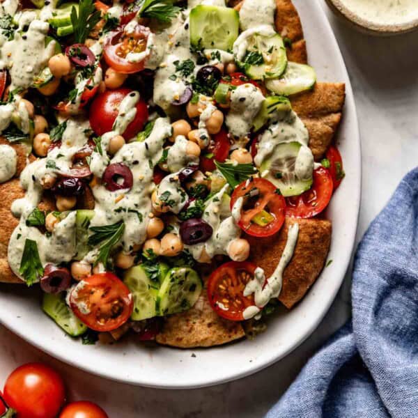 Mediterranean Nachos on a plate garnished with tahini sauce.