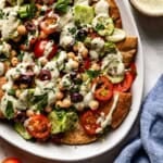 Mediterranean Nachos recipe on a plate drizzled with herbed tahini sauce.