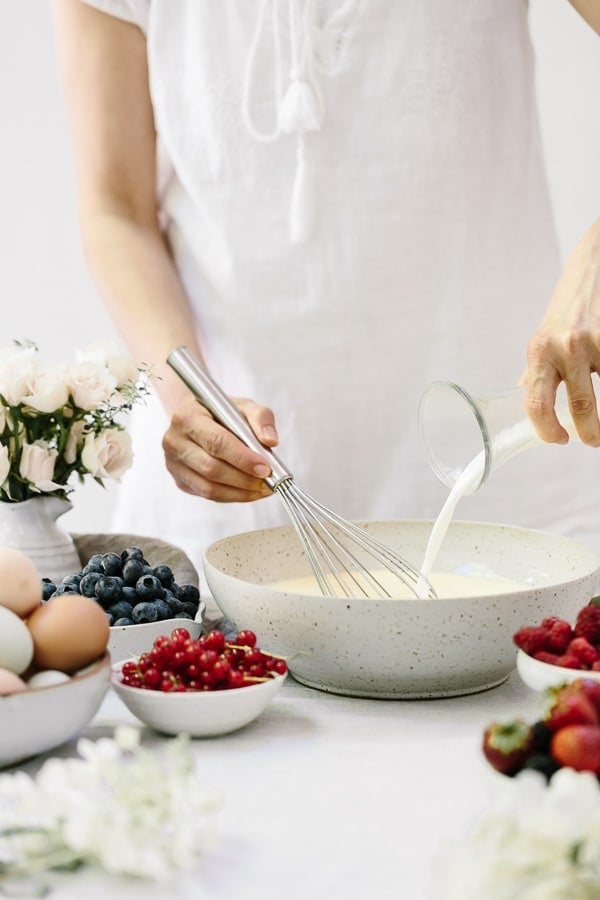 A woman is photographed from the front view as she is whisking ingredients.