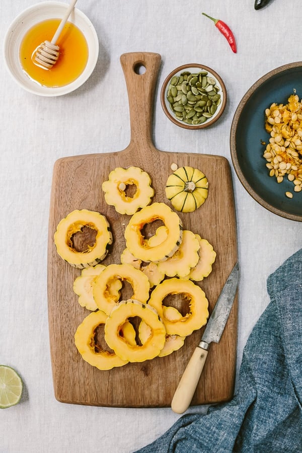 sliced Delicata Squash rings and Seeds on the side with honey in a bowl