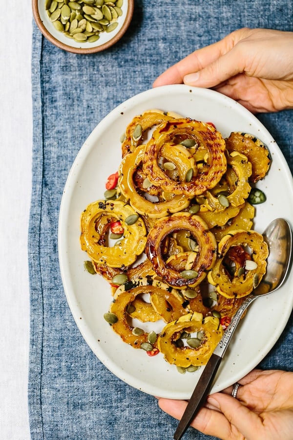 A person is serving a plate full of healthy Delicata Squash rings