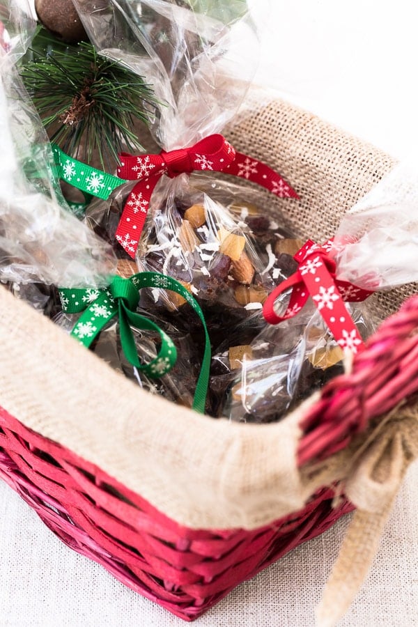 Chunks of coconut oil based and maple-sweetened dark Chocolate Almond Bark are wrapped in clear bags and placed in a basket.