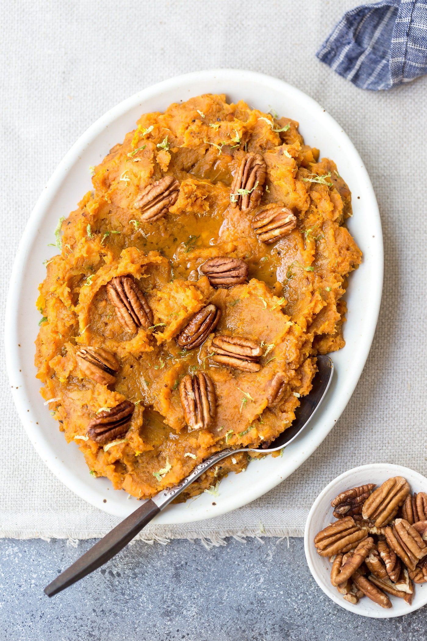 Maple sweetened easy mashed sweet potato recipe placed on an oval dish served with pecans