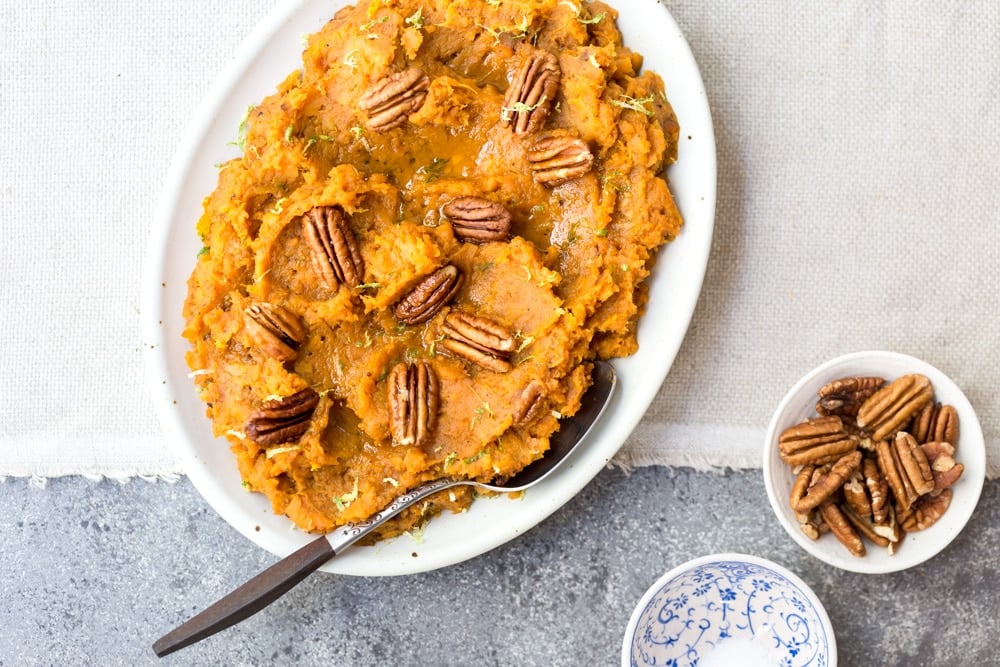 Simple Mashed Sweet Potatoes garnished with pecans in an oval plate from the top view