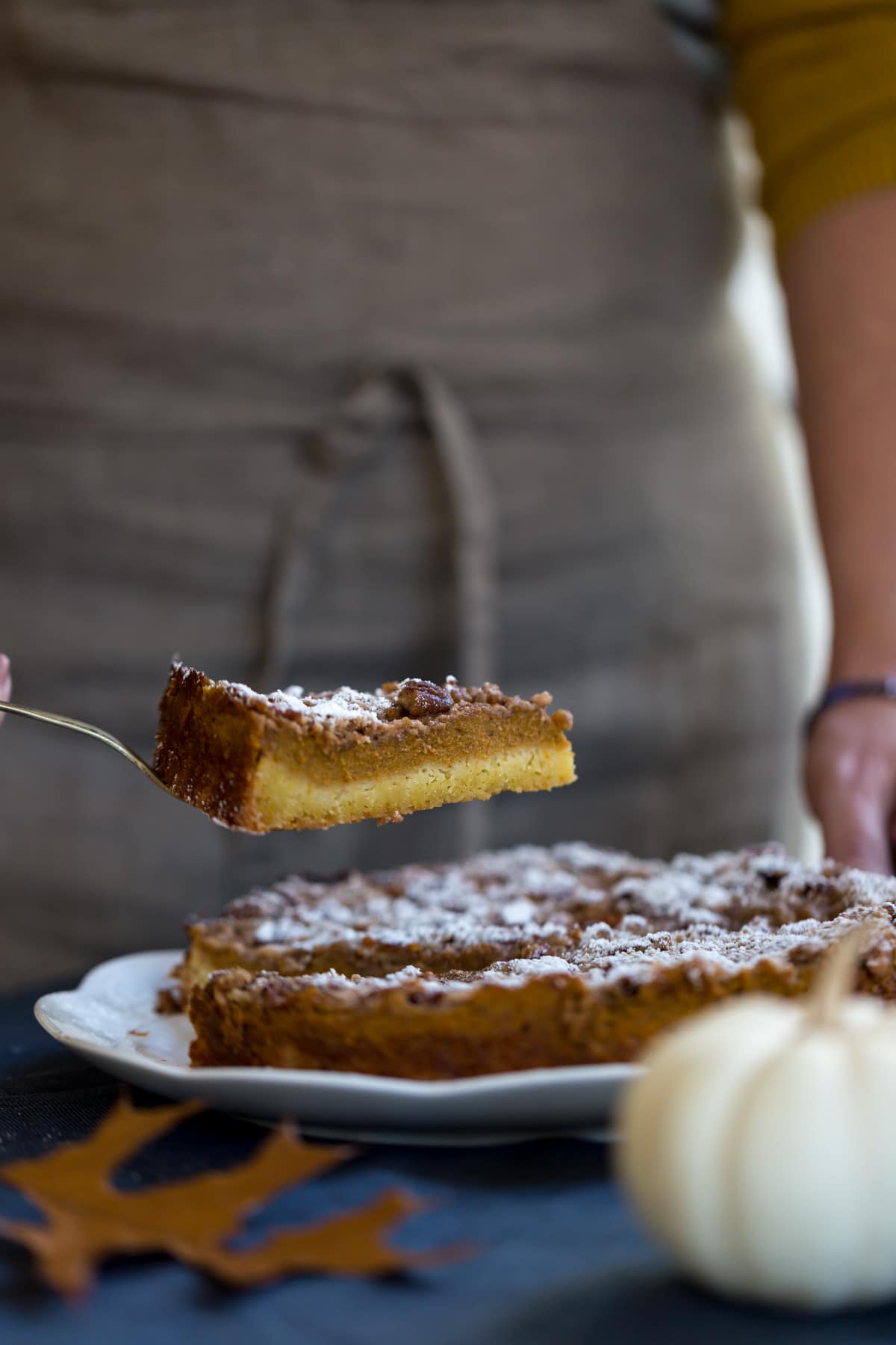 Pumpkin Pie Crumble sliced and photographed as a woman is serving it.