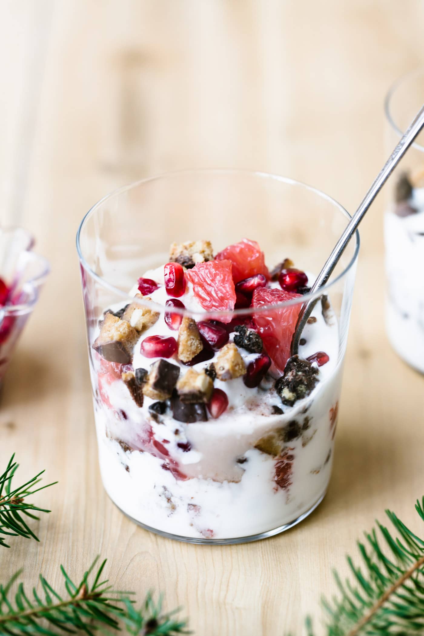 A glass full of layered yogurt parfait is topped off with seasonal fruits