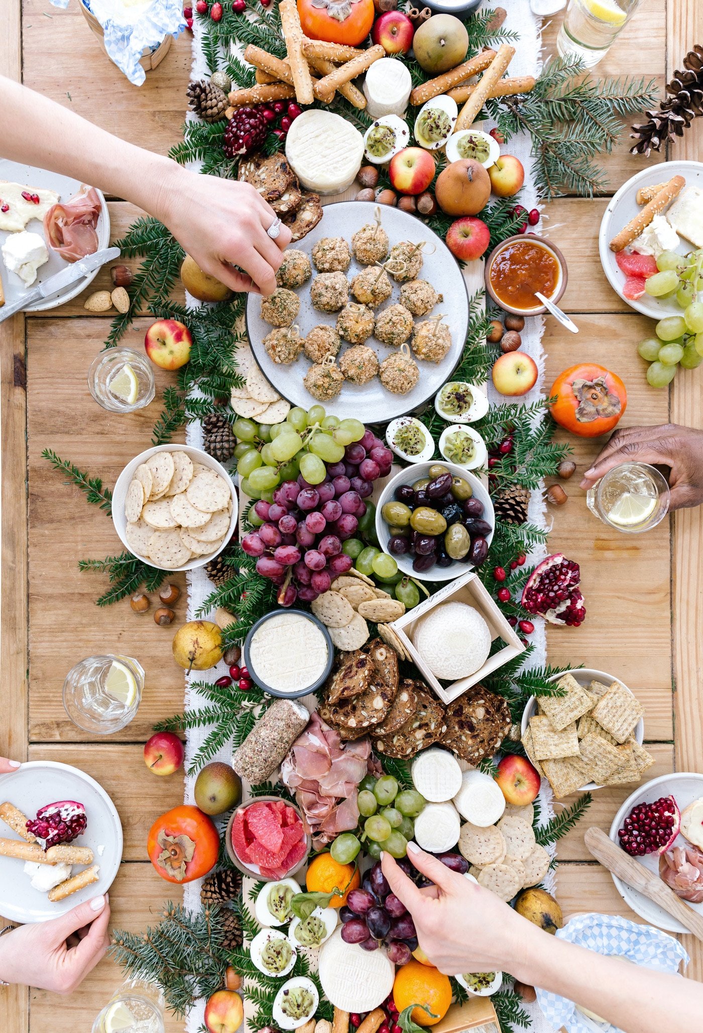 A big table set up cheese, fruit, baked goat cheese balls and people are serving themselves.