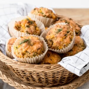 A basket full of freshly baked cornbread muffins are photographed from the front view.