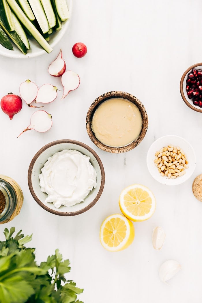 Ingredients for tahini yogurt sauce are laid out and photographed from the top view.