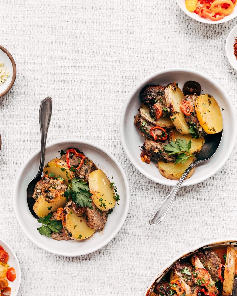 Two bowls of Turkish meatball potato bake are photographed from the top view.