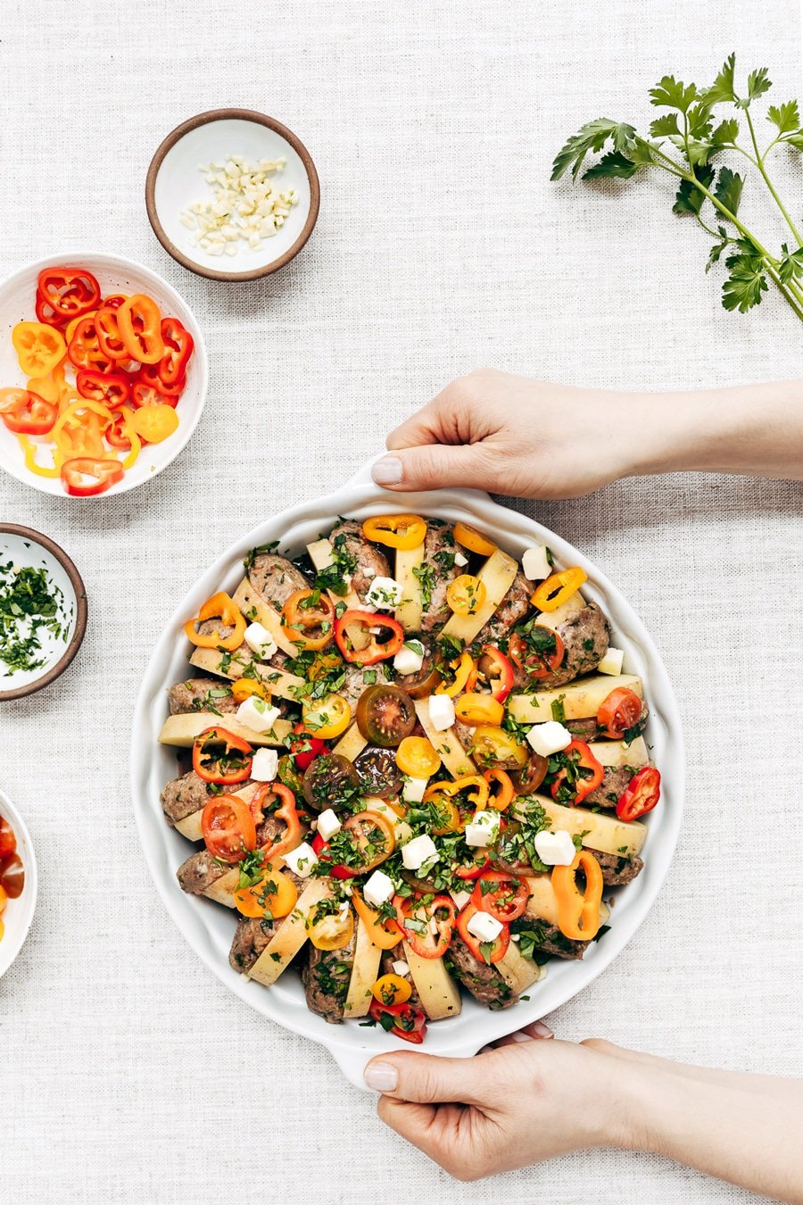 A woman is photographed from the top view as she is getting ready to place a plate of Turkish meatball potato bake.