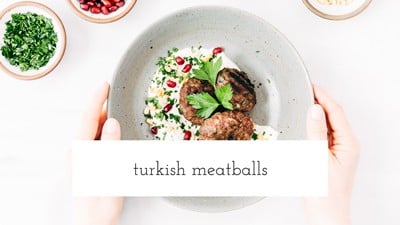 A bowl filled with Turkish Meatballs and yogurt tahini sauce placed on a marble surface and photographed from the top view.