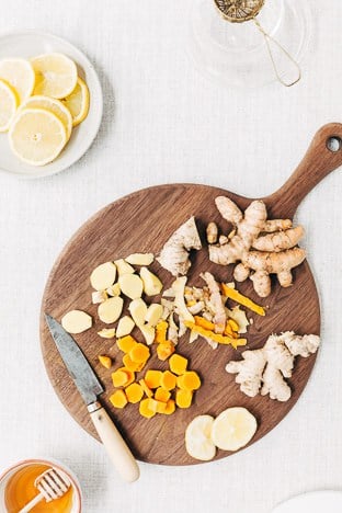 Ingredients for Turmeric Ginger Tea (turmeric, ginger and lemon) are photographed after they were peeled on a wooden cutting board from the top view