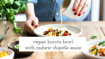 a woman is photographed as she is drizzling cashew cream sauce with chipotle over a bad of vegan burrito bowl.