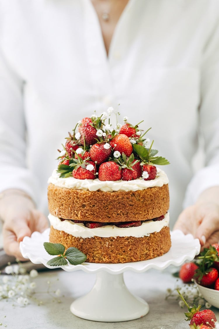 One of the recipes Ways to use almond flour Round Up: A woman is photographed from the front view as she is serving a strawberry almond flour cake