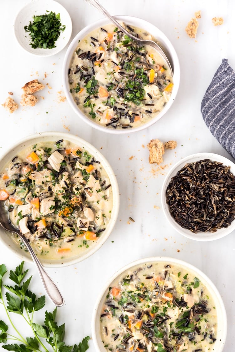 Three bowls of Lightened-Up Creamy Chicken and Wild Rice Soup are photographed from the top view.