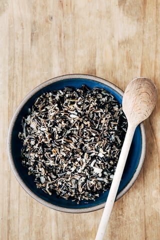 A bowl of cooked wild rice is photographed from the front view for the how to cook wild rice recipe post