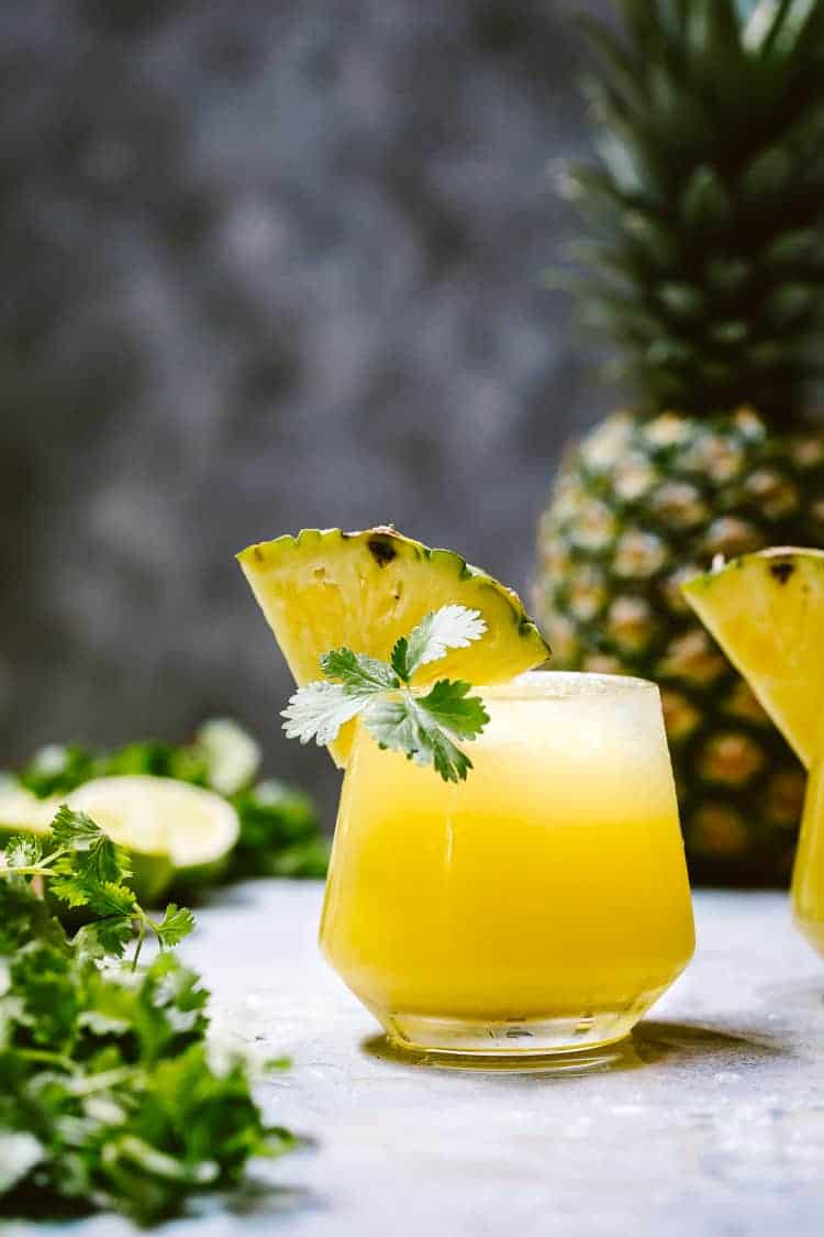 Pineapple Mezcalitas garnished with a wedge of pineapple and cilantro