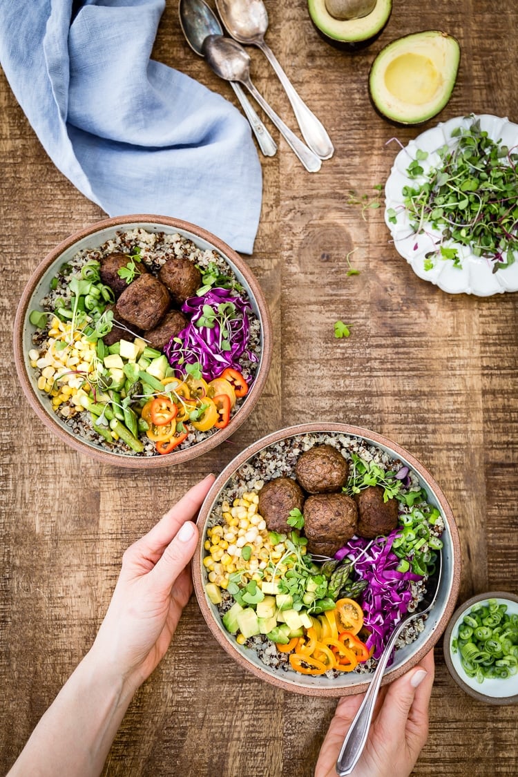 a woman is photographed from the top view as she is serving a few bowls of quinoa power bowl dishes.