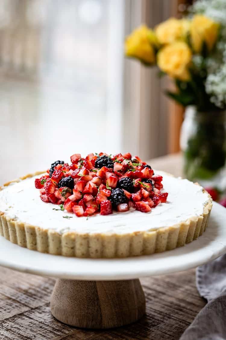 Strawberry and Mascarpone Tart on a cake stand with roses in the background