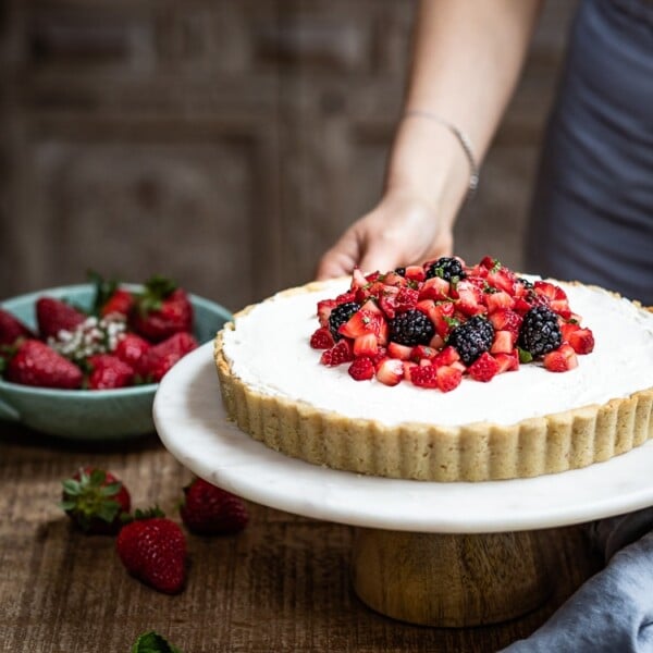 Strawberry Mascarpone Tart in almond flour crust being served by a woman