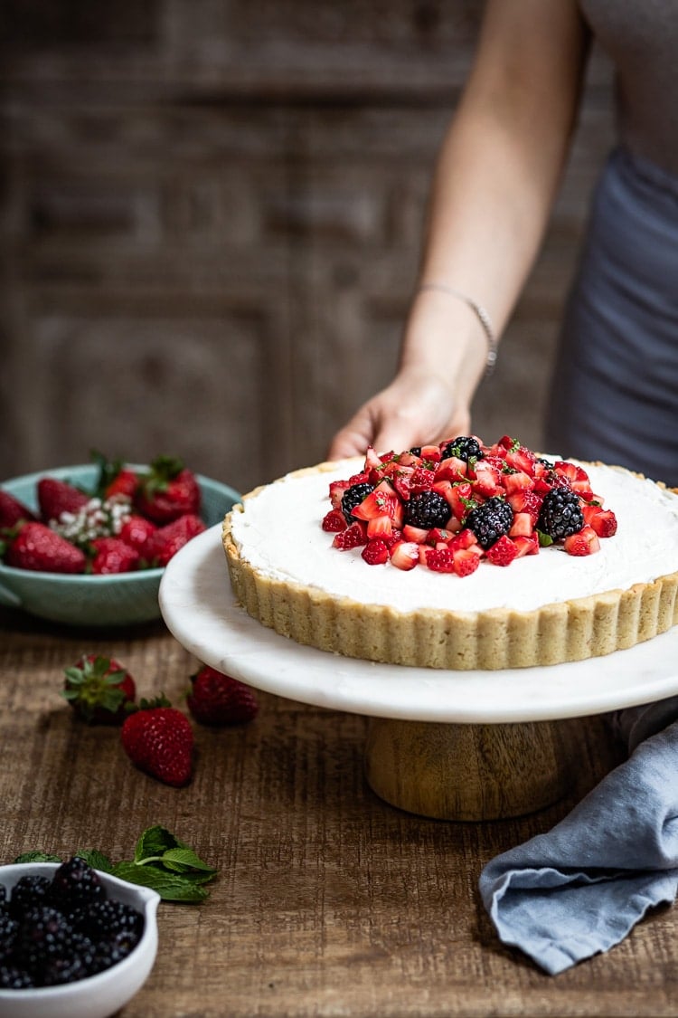 Strawberry Mascarpone Tart in almond flour crust being served by a woman