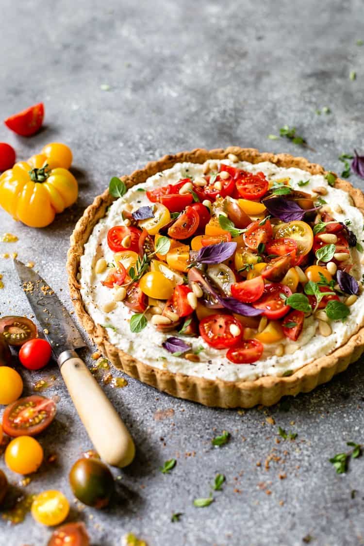 Ricotta and Cherry Tomato tart garnished with purple basil and a knife on the side