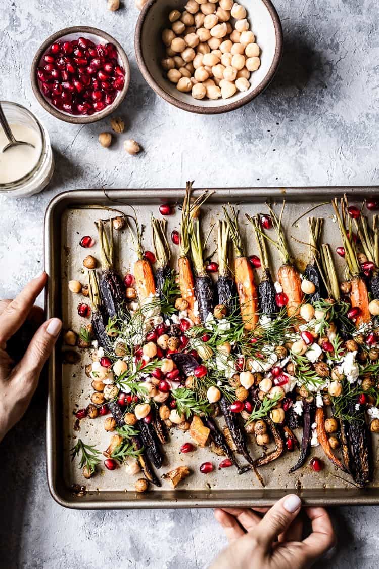 Roasted Whole Carrots topped off with tahini dressing served by a woman