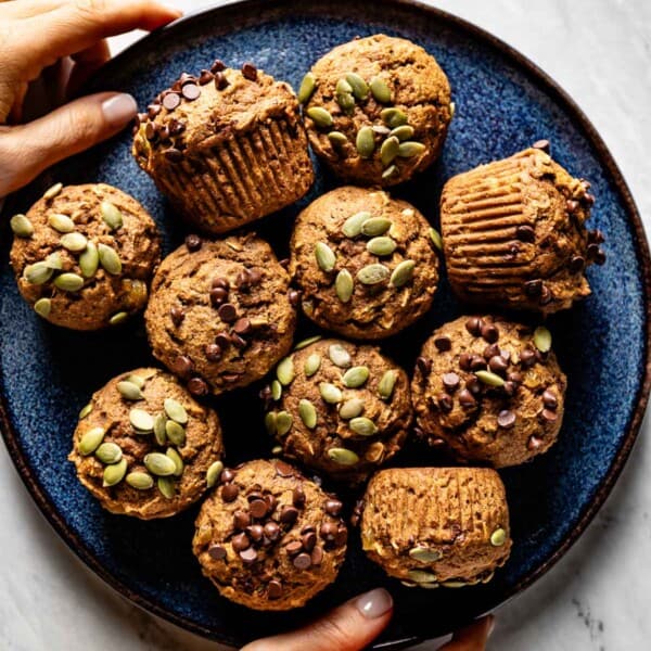 Pumpkin oatmeal muffins on a plate being served by a person.