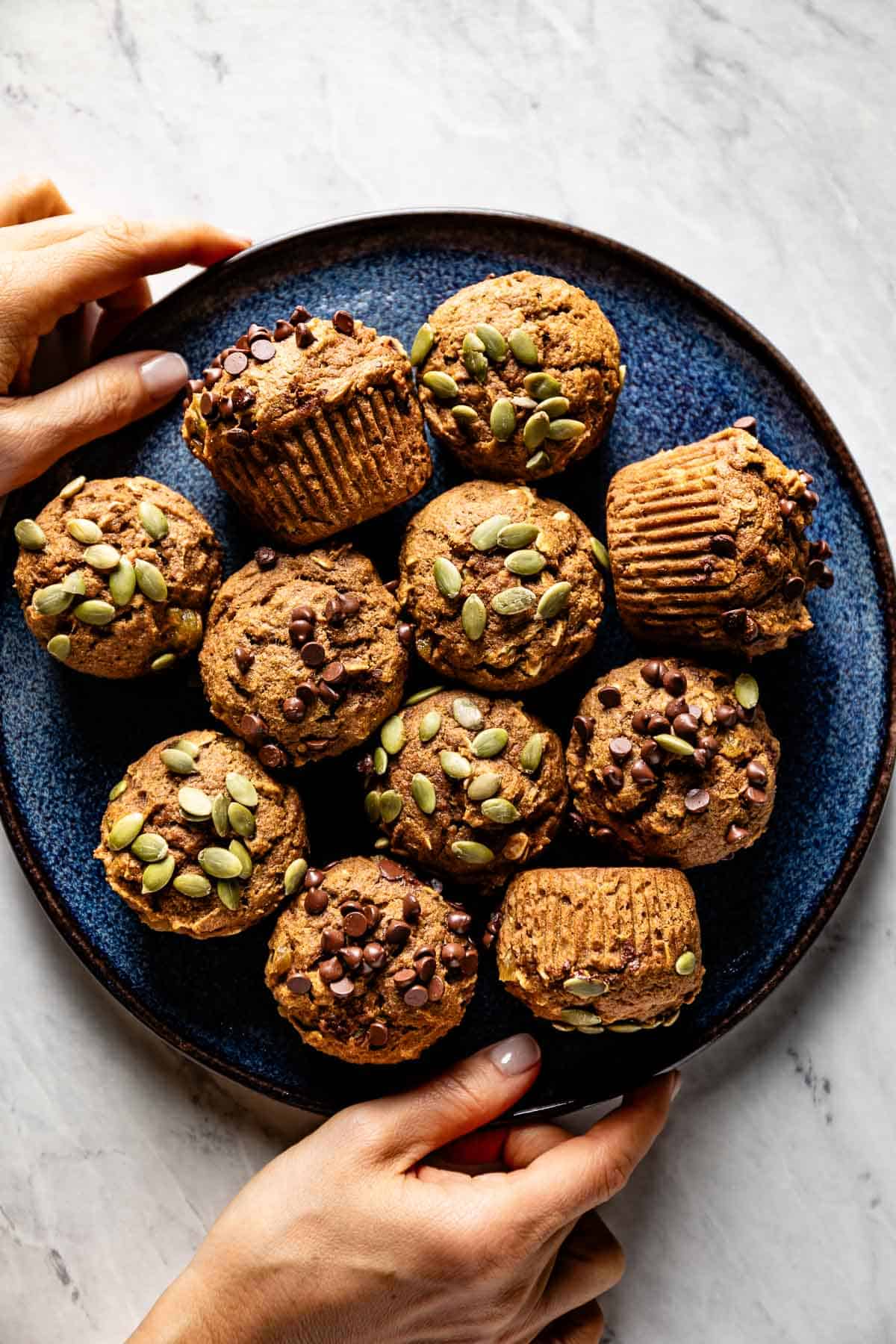 Pumpkin oatmeal muffins on a plate being served by a person.