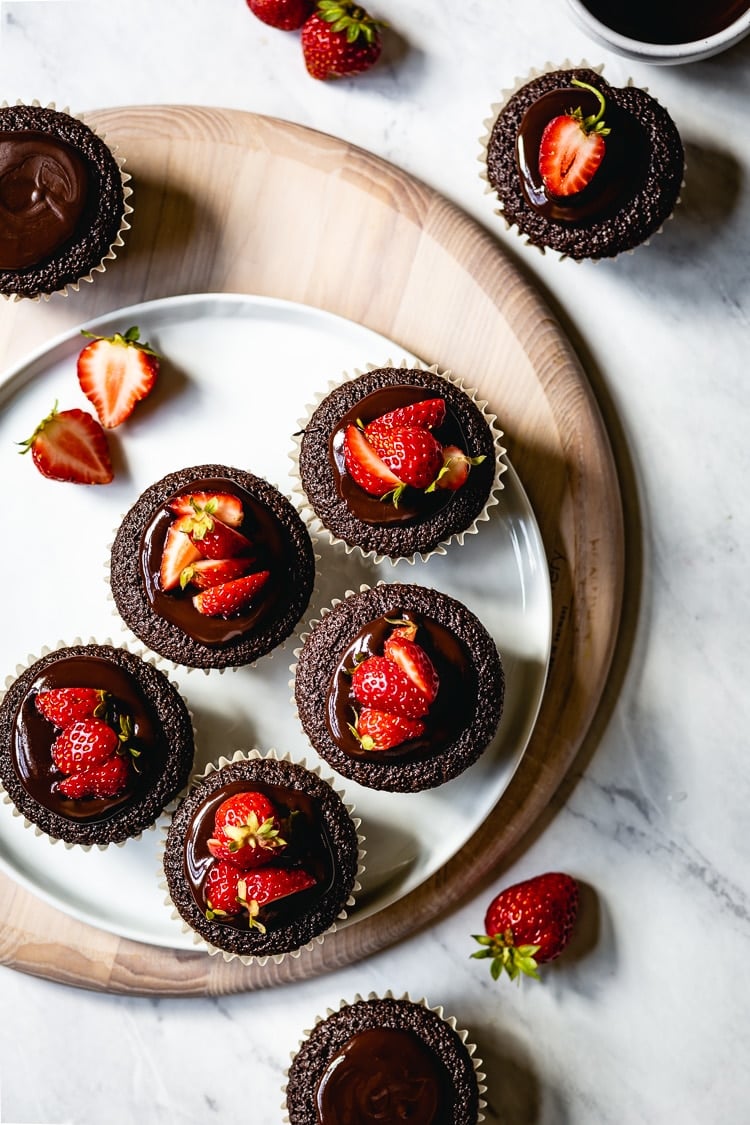 flourless cupcakes topped off with chocolate and strawberries on a plate
