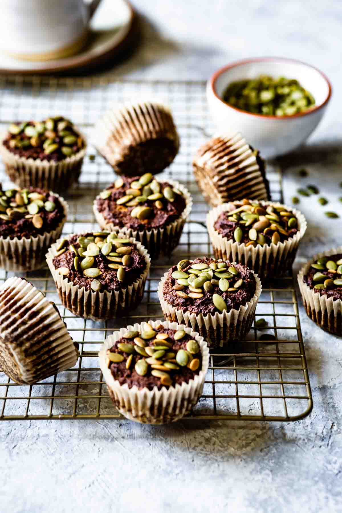 Paleo Pumpkin Muffins with almond flour cooling on a rack with pumpkin seeds on the side