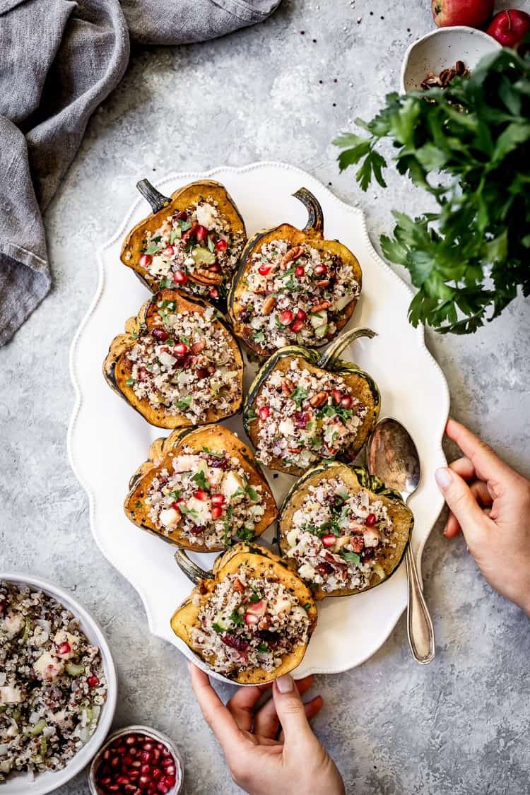 Roasted Vegan Stuffed Acorn Squash placed on a plate being served by a woman