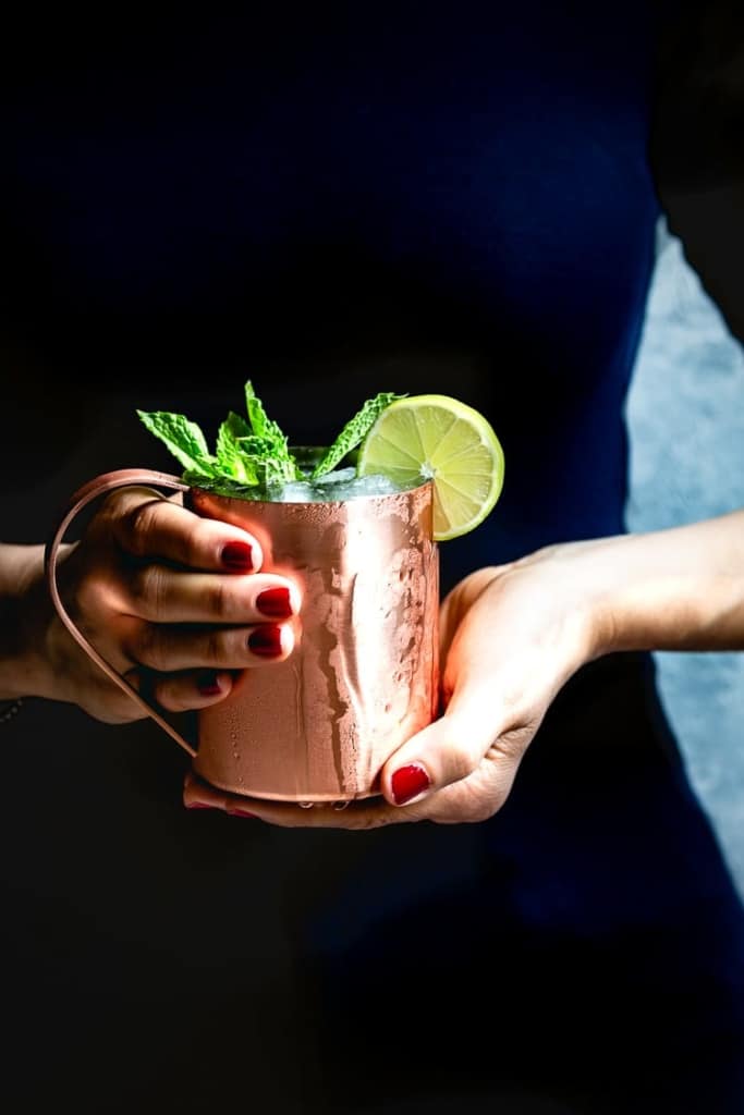 Moscow Mule Recipe garnished with mint held by a woman.