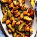 Roasted Sweet Potatoes and Brussels Sprouts on a plate with a spoon on the side.