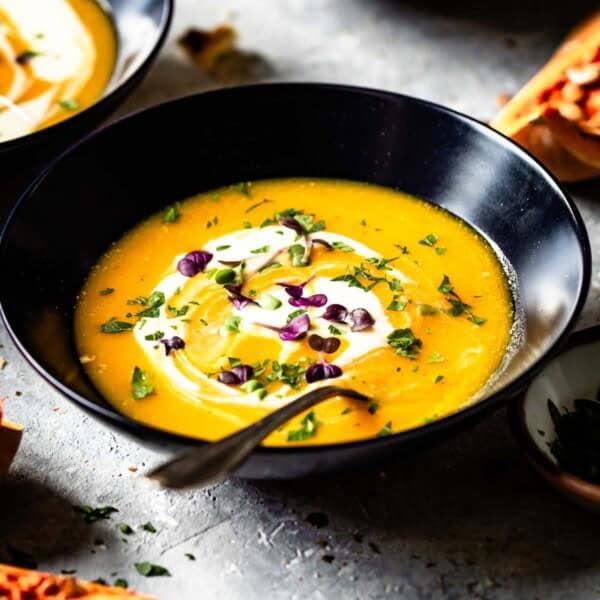 A bowl of vegetarian butternut squash soup with a spoon in the bowl.