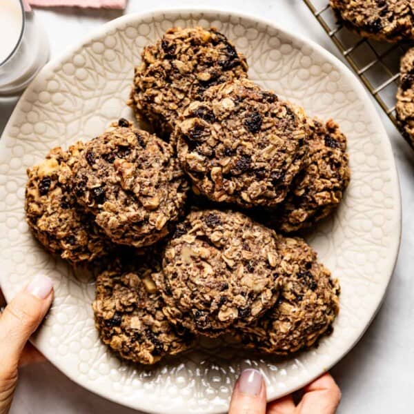 Healthy oatmeal raisin cookies placed on a plate being served by a person.