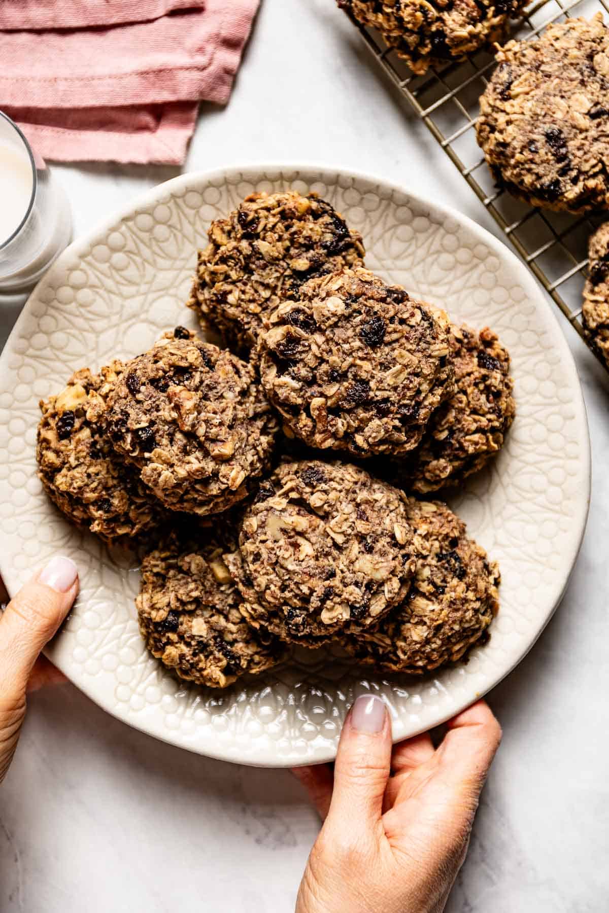Healthy oatmeal raisin cookies placed on a plate being served by a person.